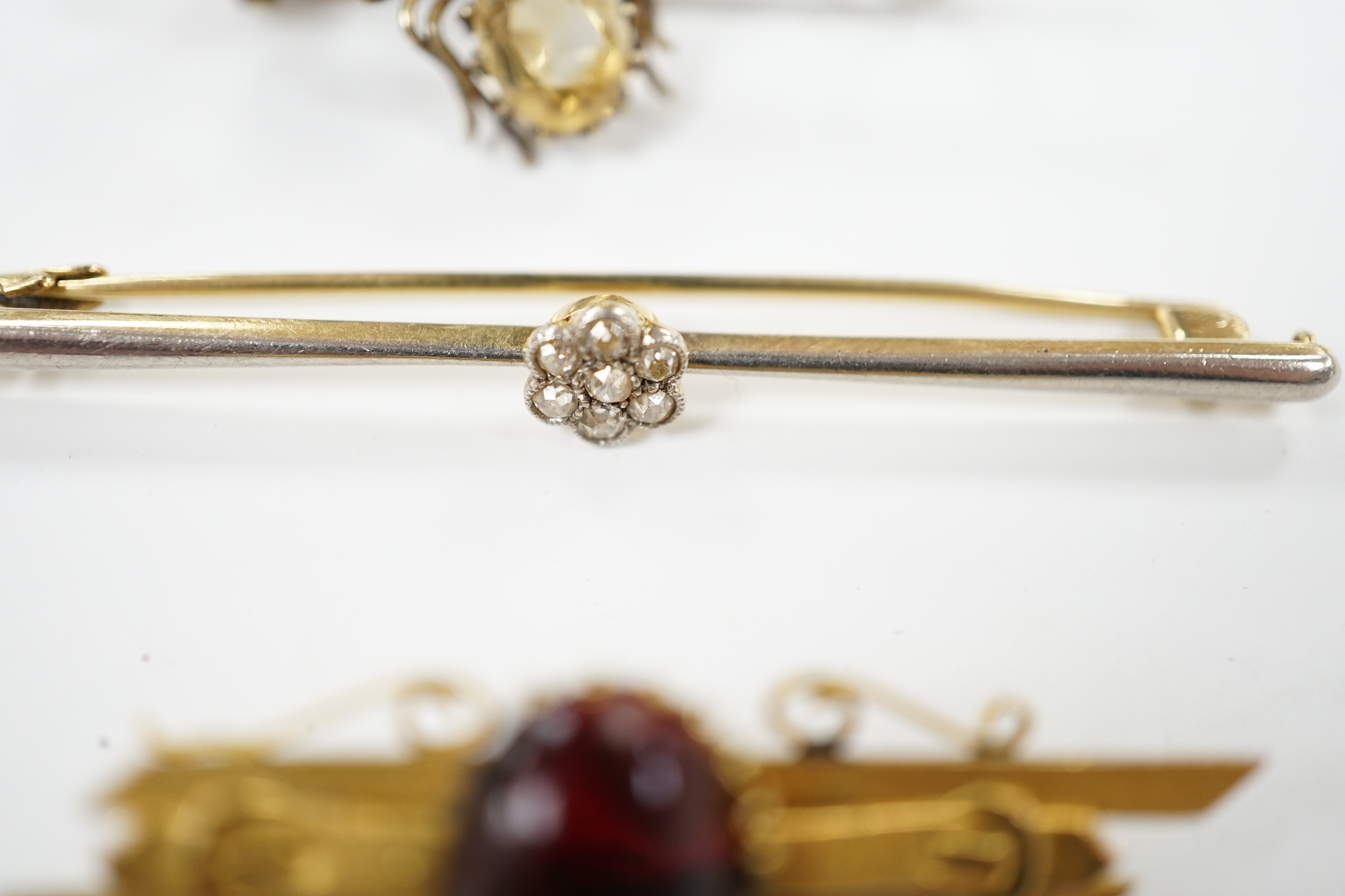 An Edwardian 15ct and diamond cluster set bar brooch, 60mm and two other gem set bar brooches including a bug brooch.